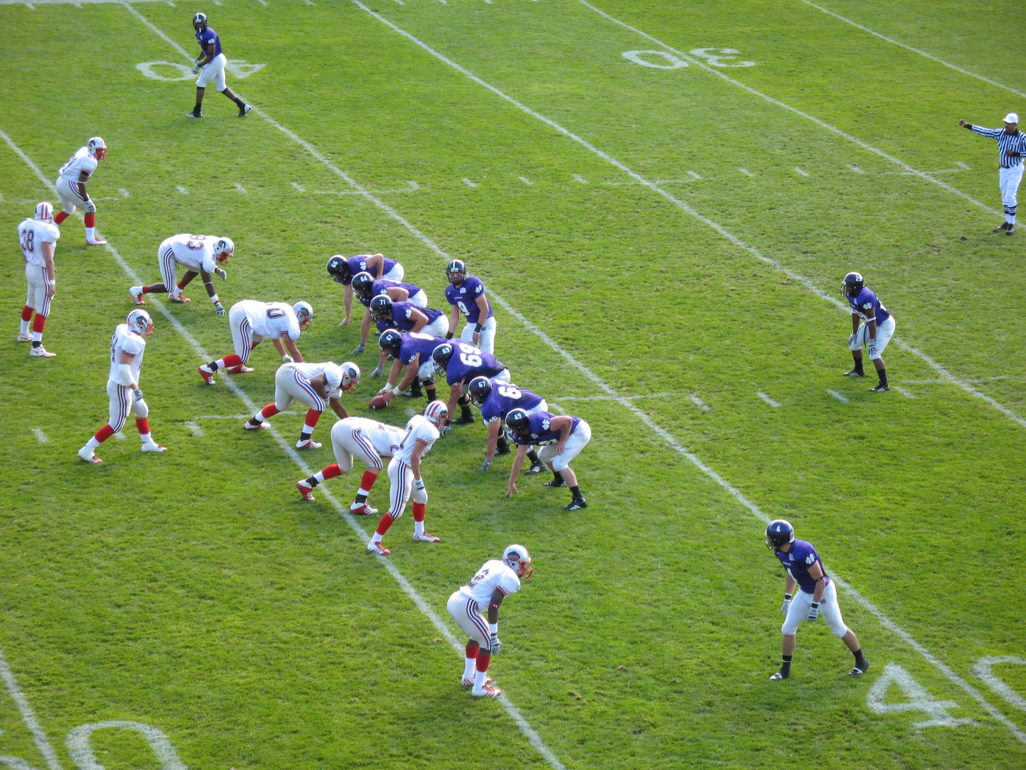 Players assemble at the line of scrimmage in an American football game.
