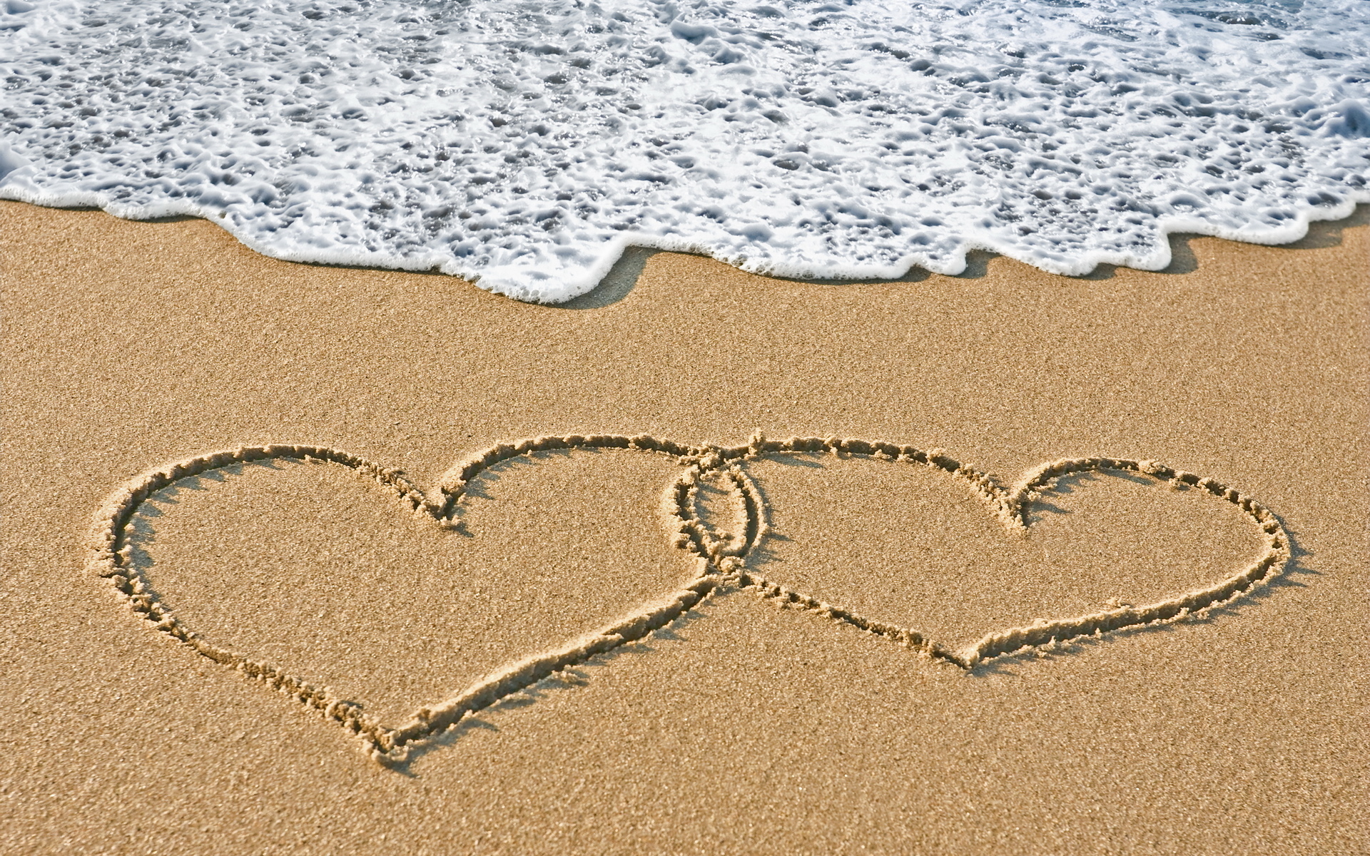 Sand hearts couple at the beach